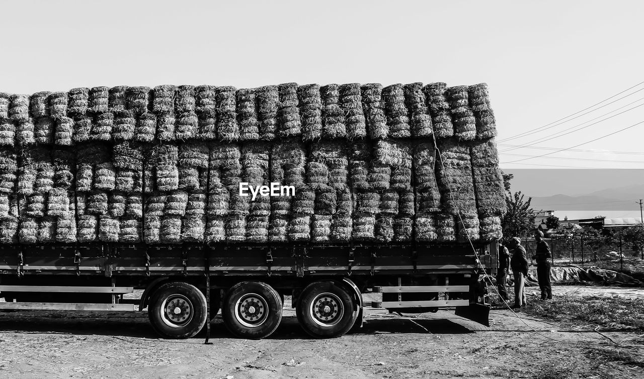 Stack of hay bales on truck against sky