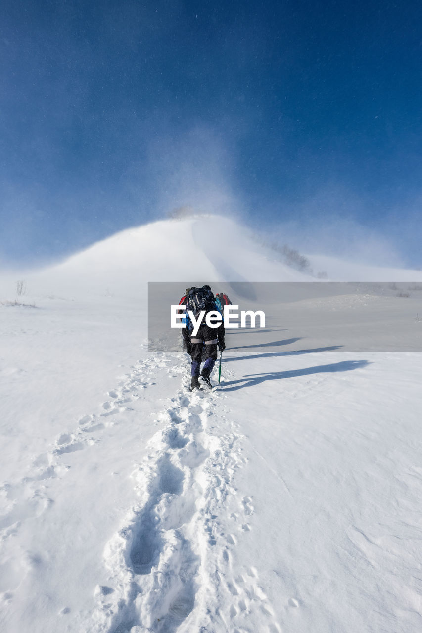 People walking on snow against sky