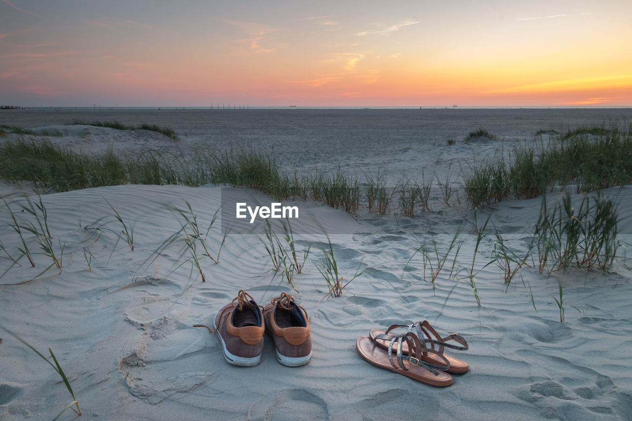 High angle view of shoes on beach against sky during sunset