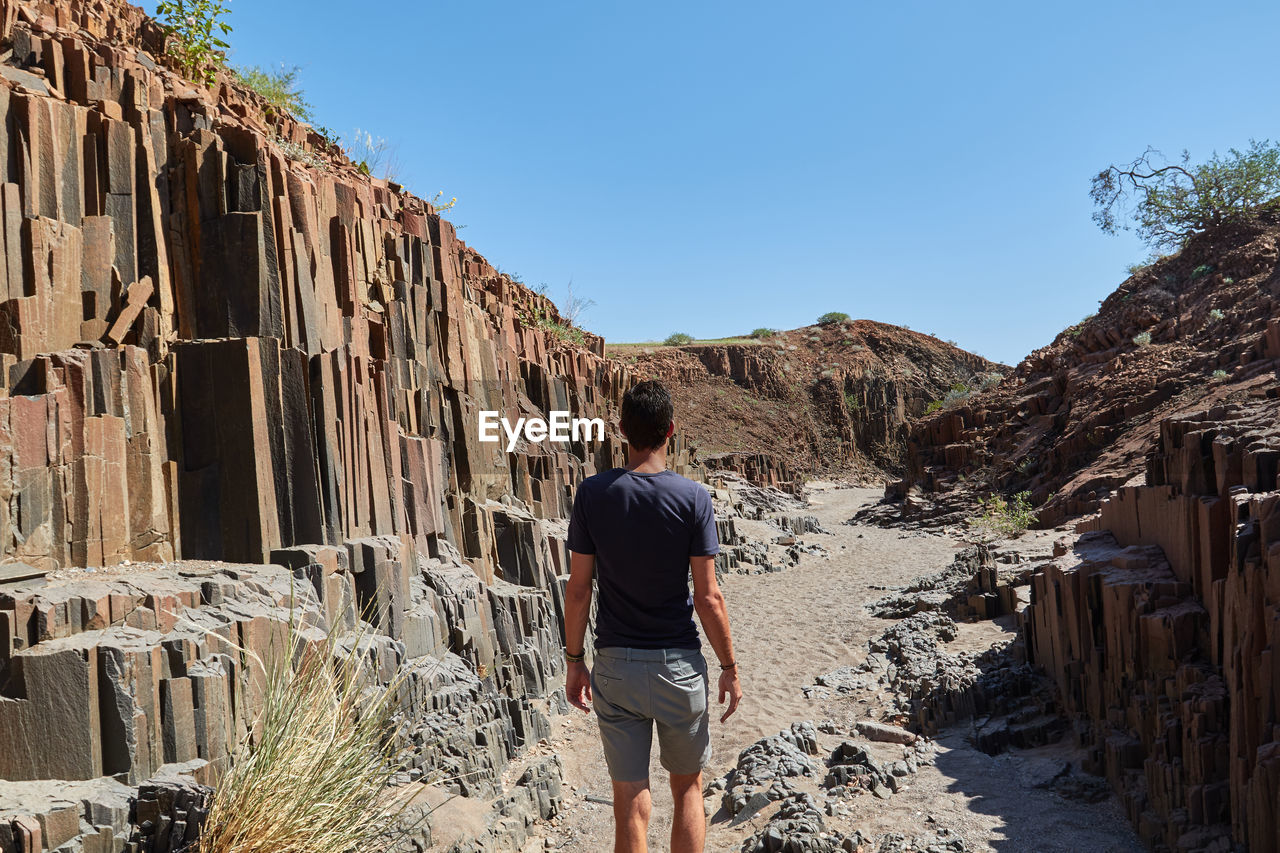 Rear view of man walking on land against sky