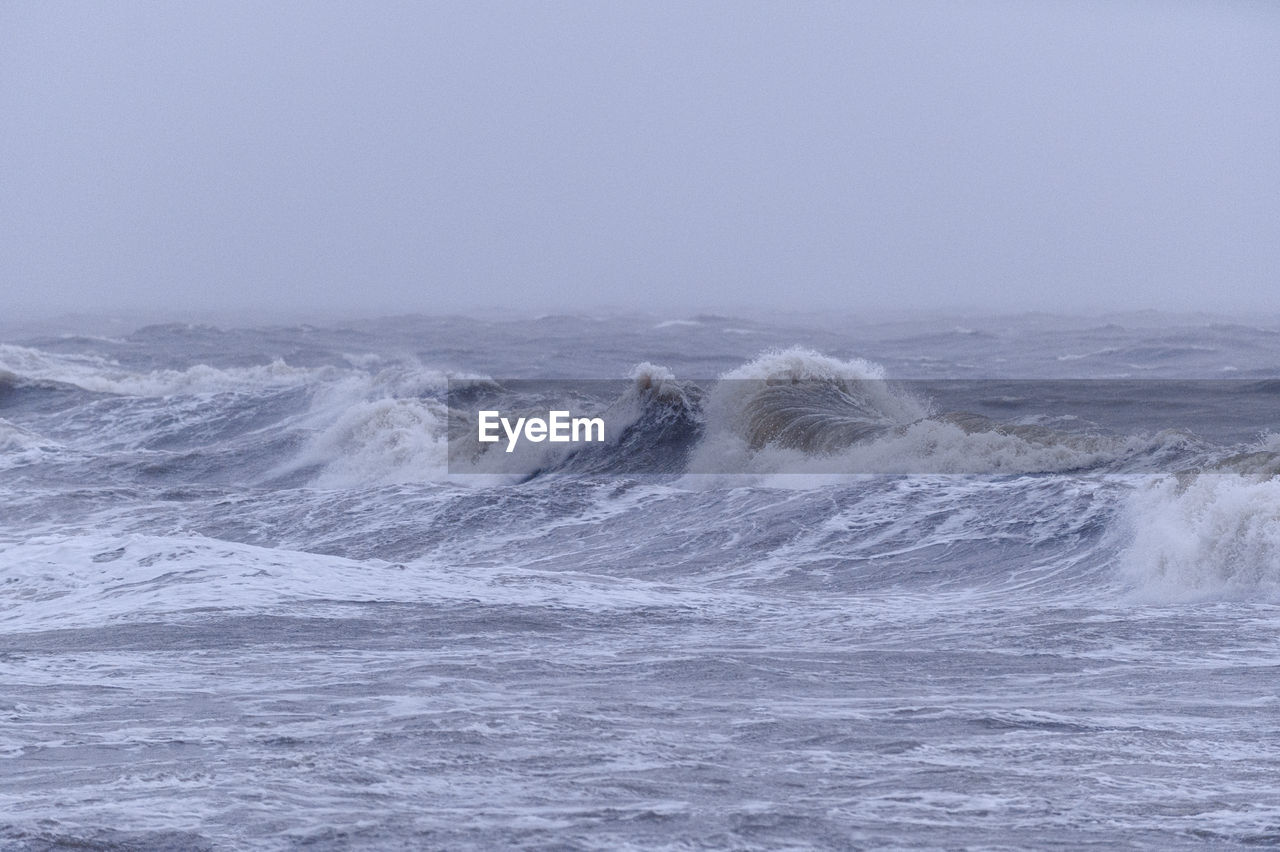 SCENIC VIEW OF WAVES IN SEA AGAINST CLEAR SKY