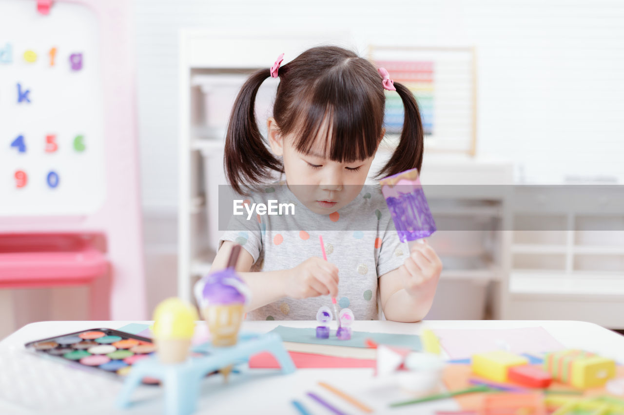 Young girl decorating hand made craft for homeschooling