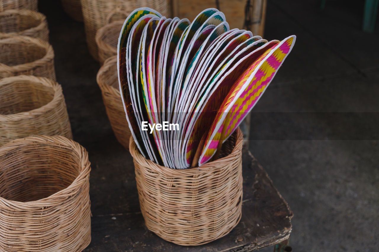 Close-up of bamboo hand fans in wicker basket at store