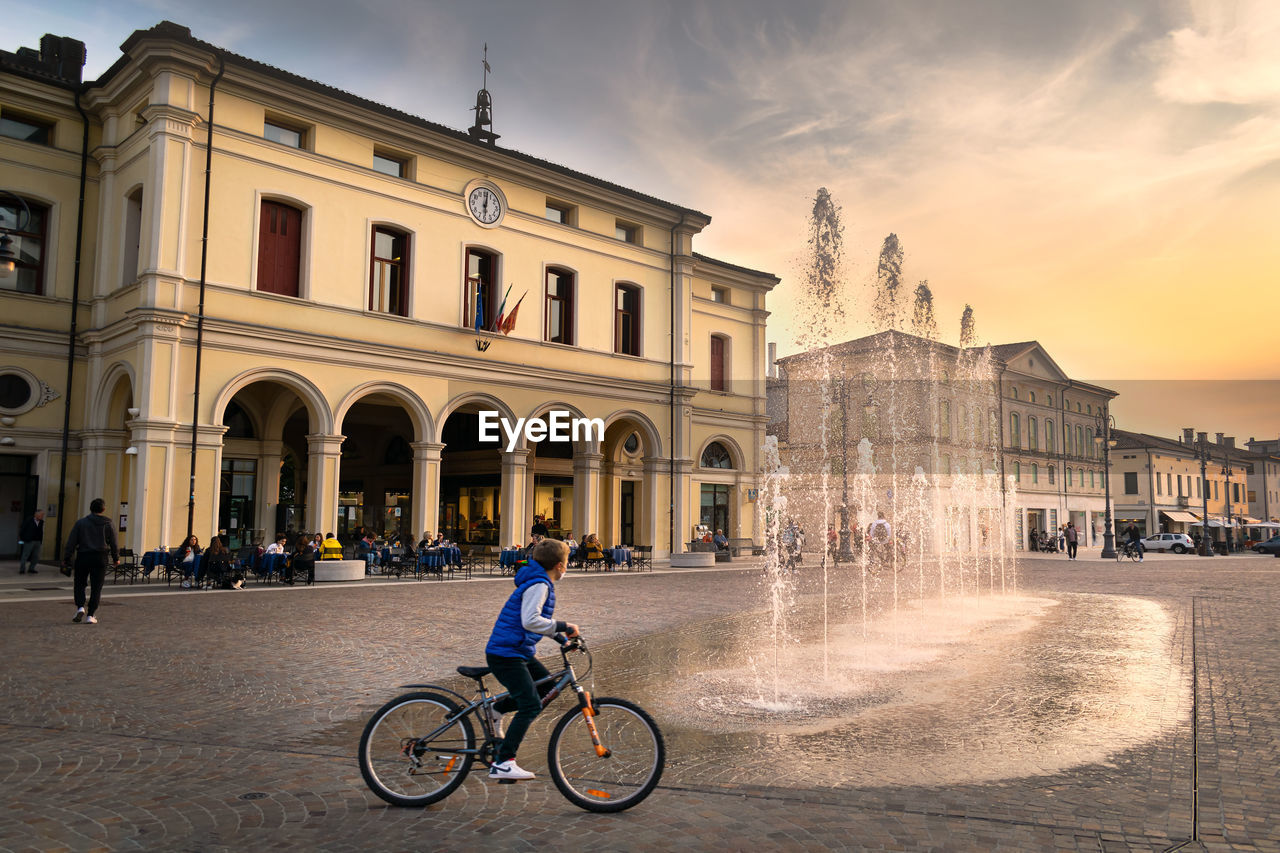 MAN RIDING BICYCLE BY BUILDING IN CITY