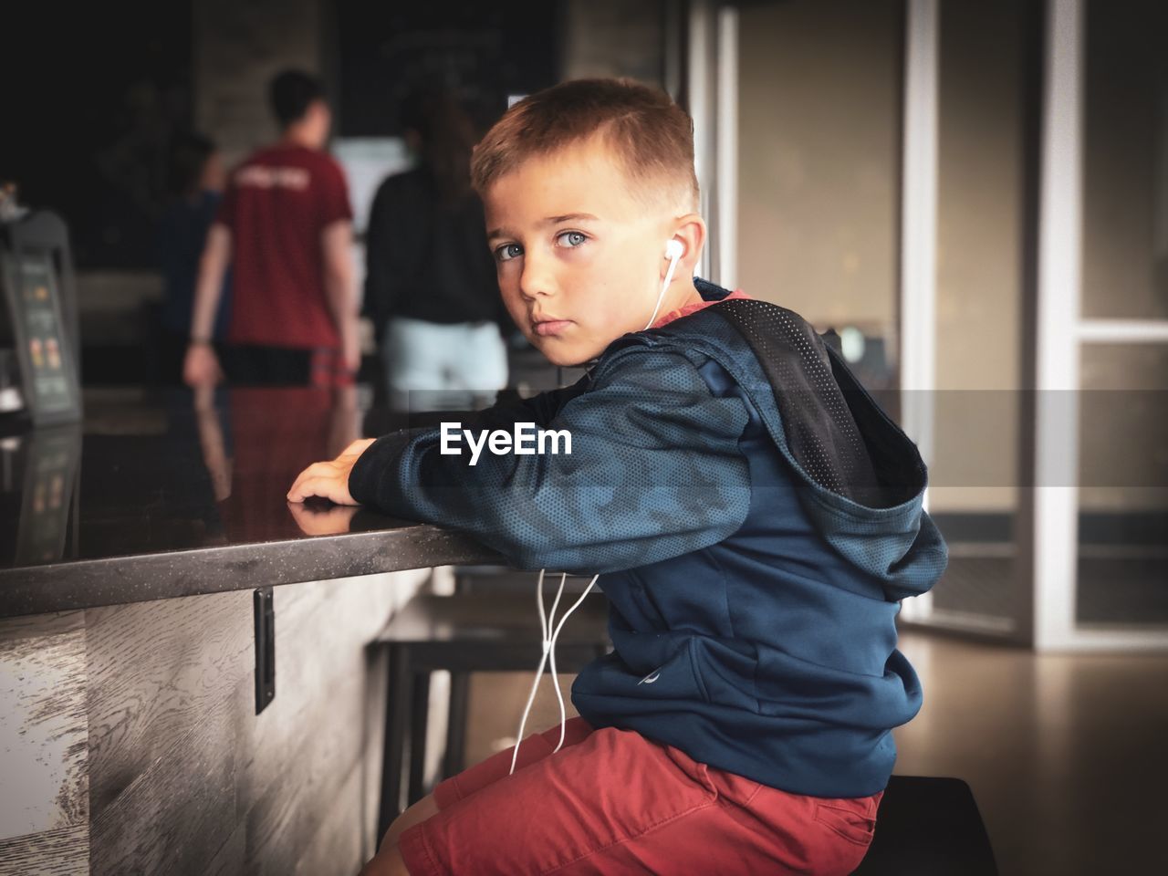 Portrait of cute boy listening music on stool