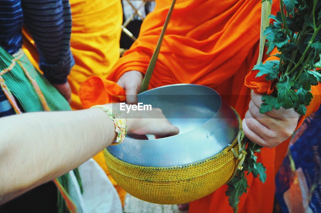 Cropped hand over container being held by monk