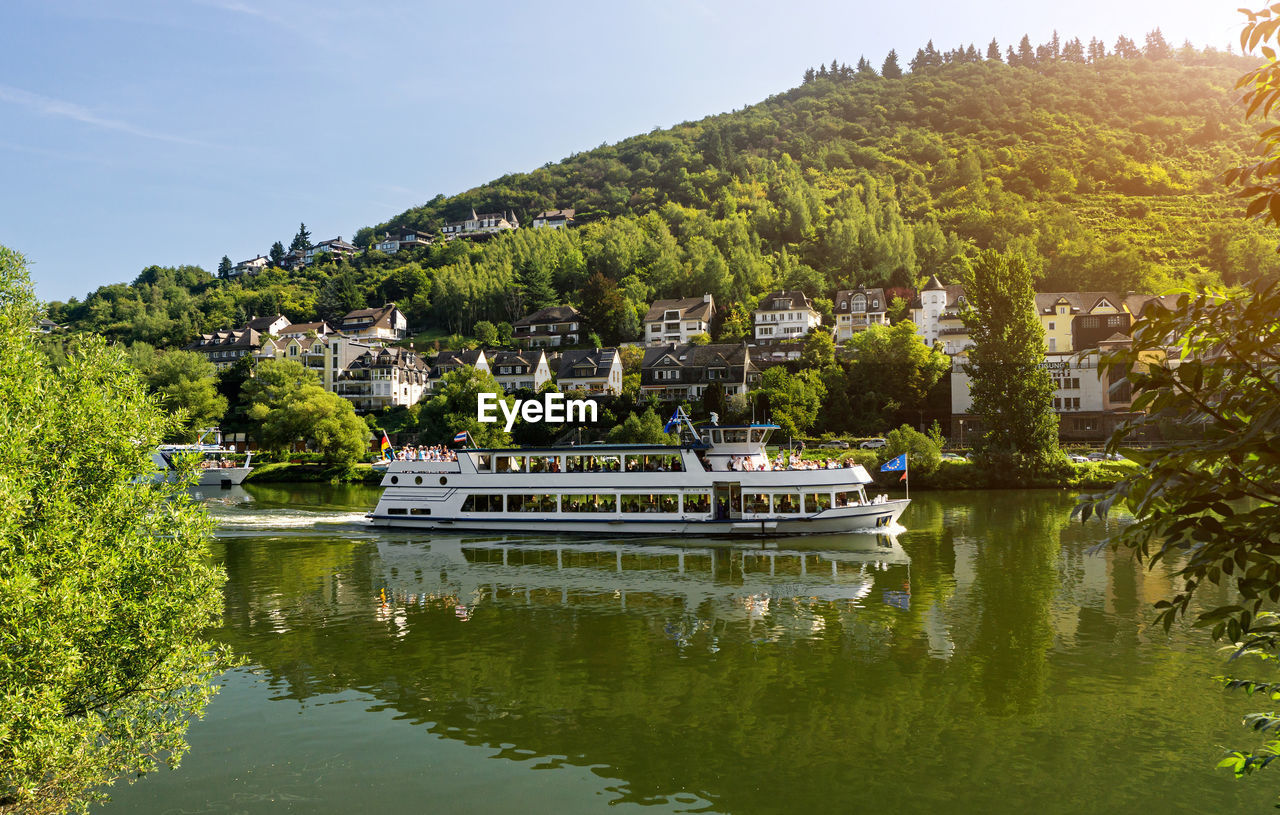 Boats moored on lake by trees against sky