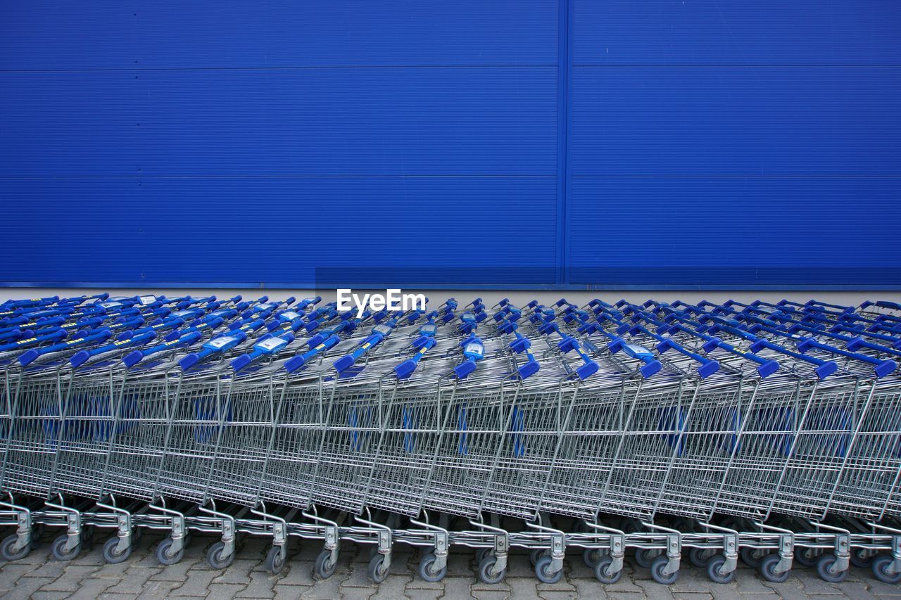 Shopping trolleys arranged against blue wall