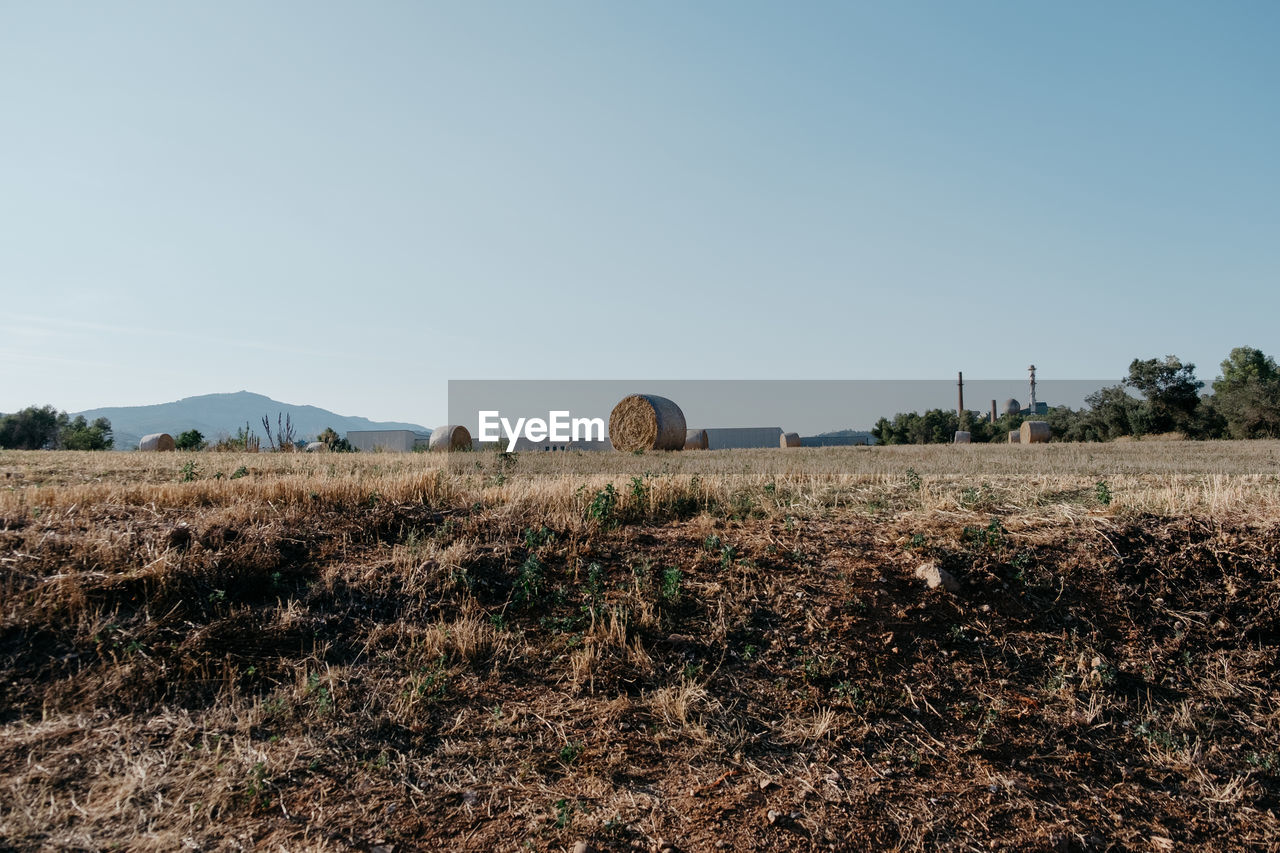 Hay bale on field against clear sky