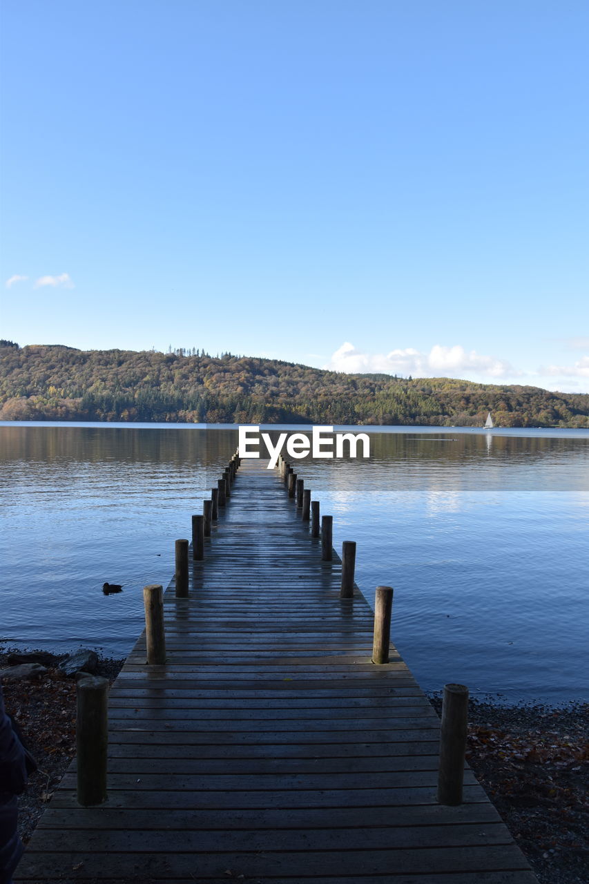 Pier over lake against clear blue sky