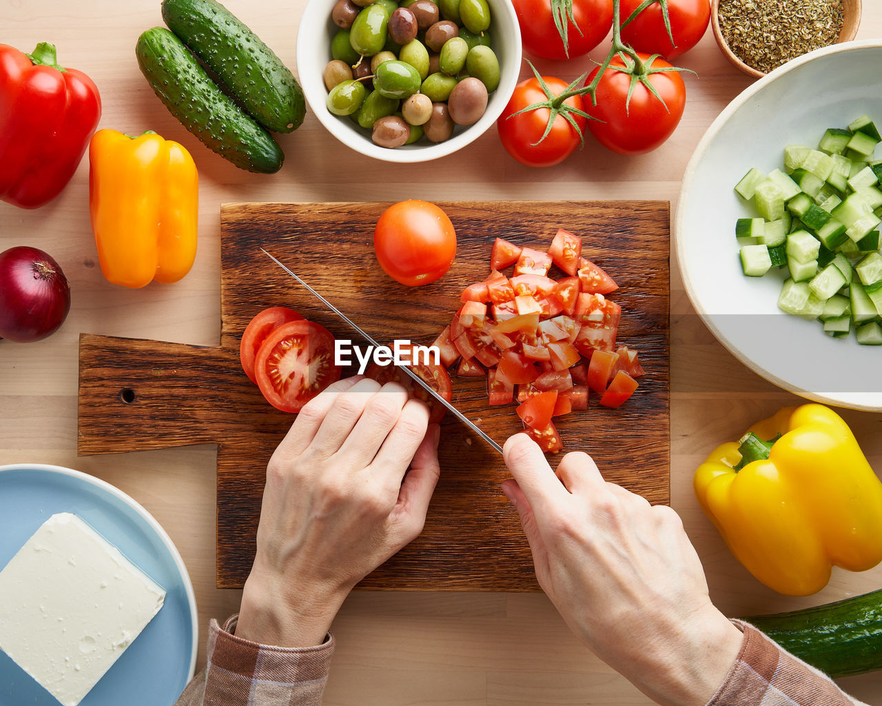 Step by step recipe for salad horiatiki, wooden board for cutting vegetables and ingredients. 