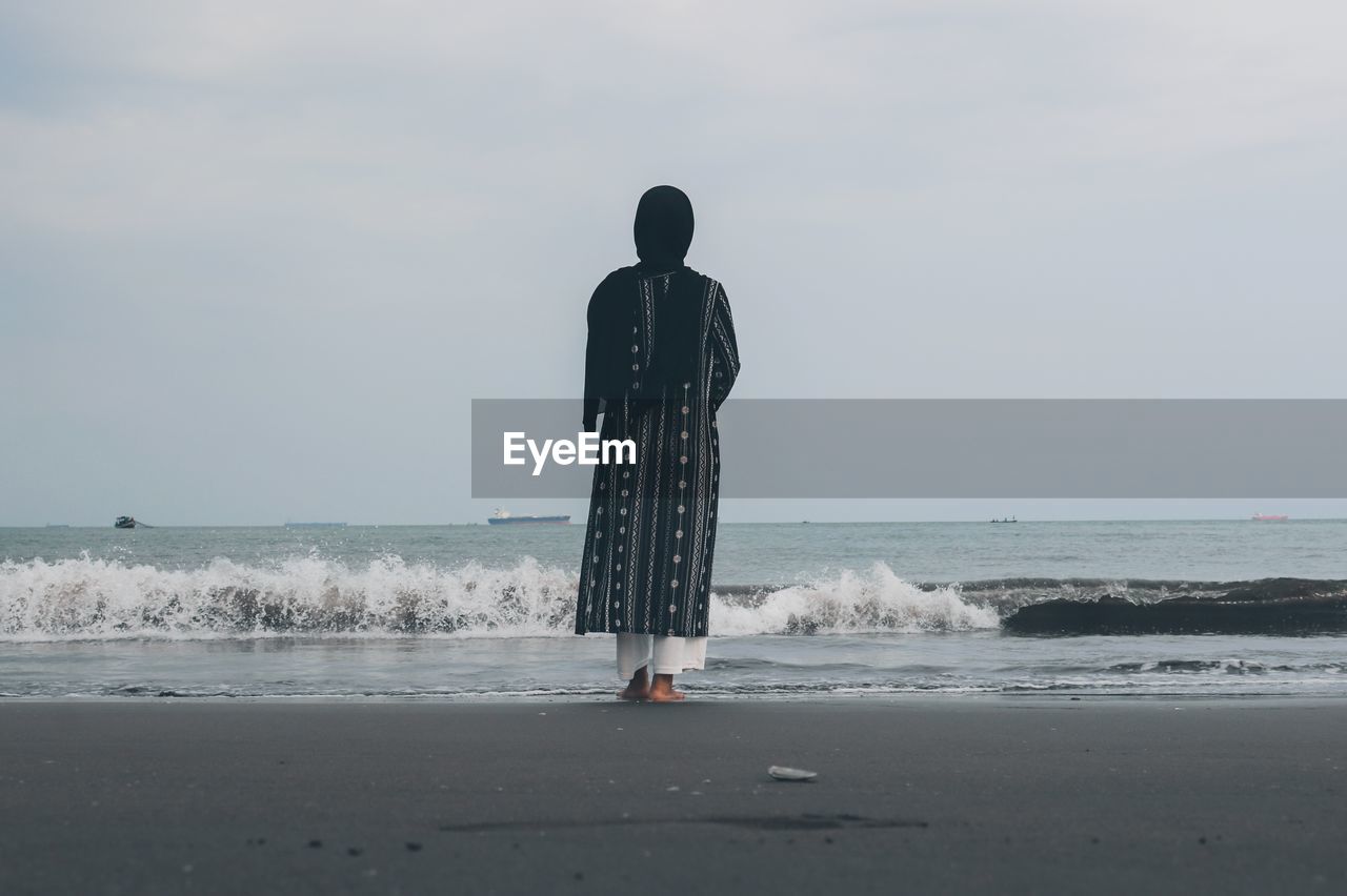 Rear view of woman standing at beach