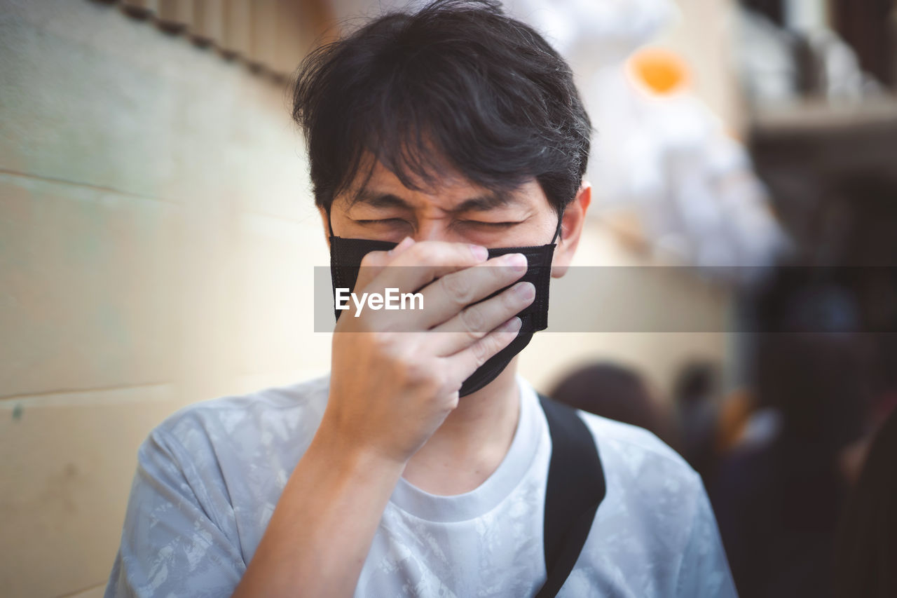 Close-up of man wearing mask coughing outdoors