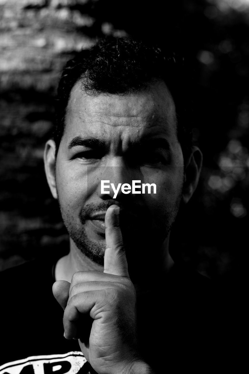 Close-up portrait of mature man with finger on lips