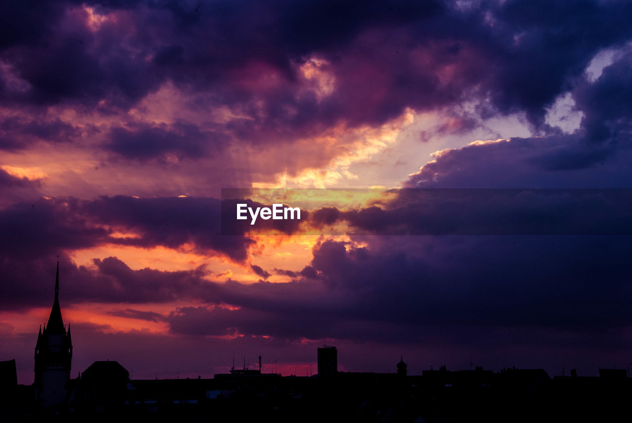 Silhouette of city against dramatic sky