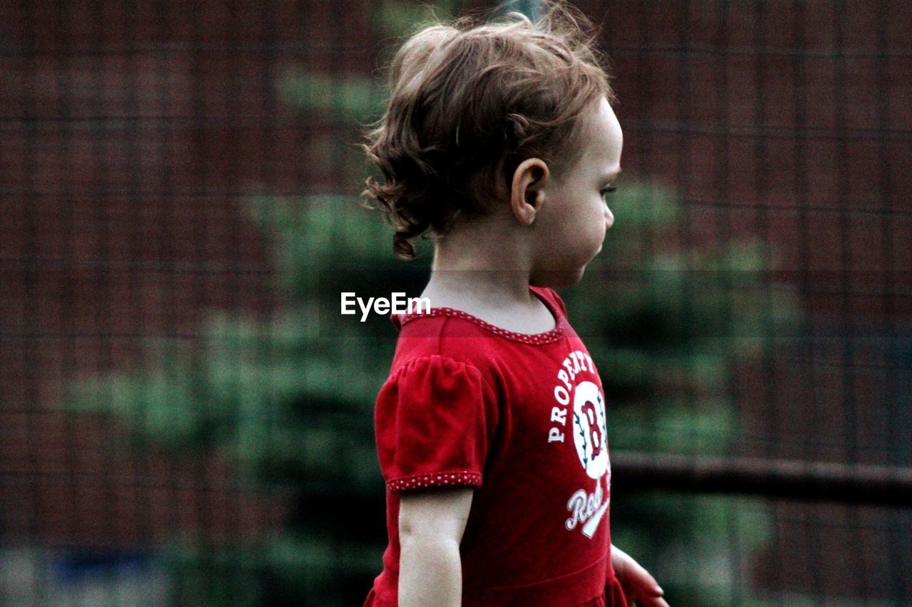 Side view of cute baby girl looking away while standing outdoors