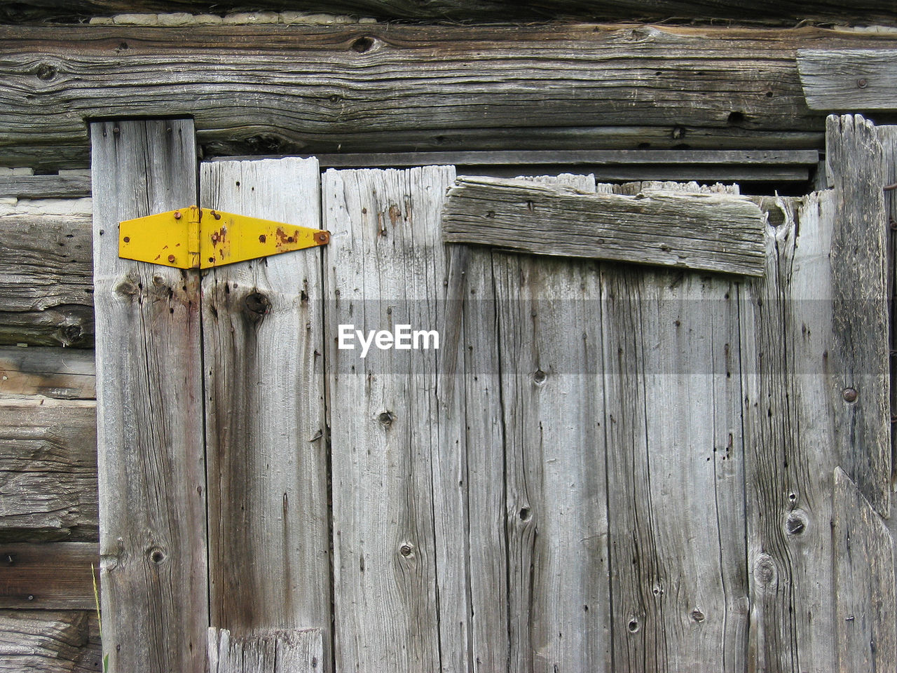 Close-up of yellow hinge on old wooden door