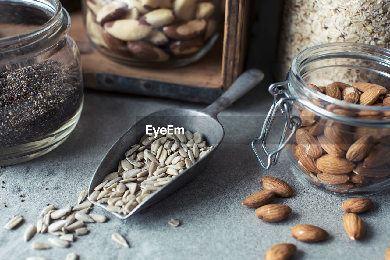 Close-up of seeds in serving scoop with almonds in jar on kitchen counter