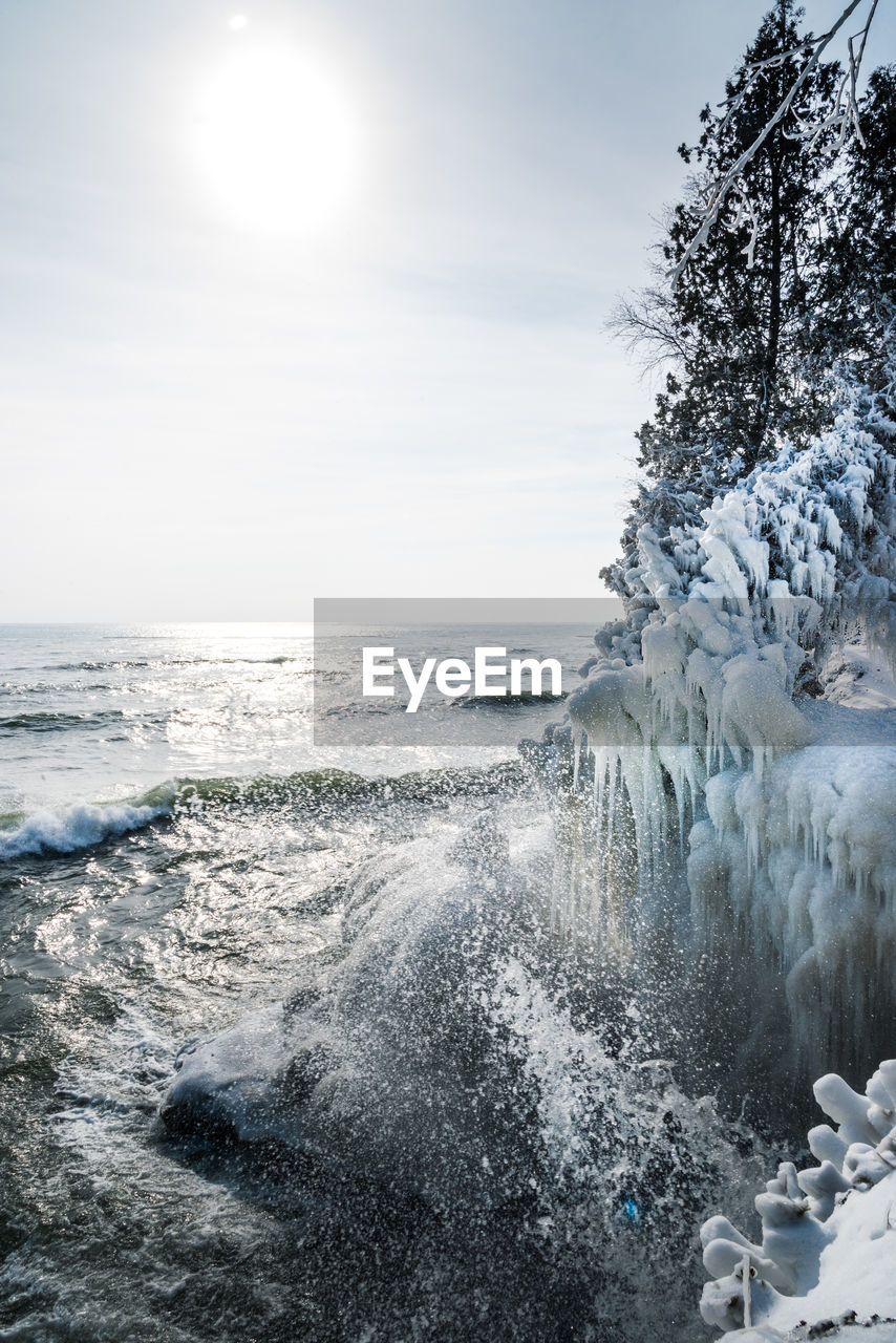 Waves crashing on ice covered shoreline at cave point park door county wisconsin in winter