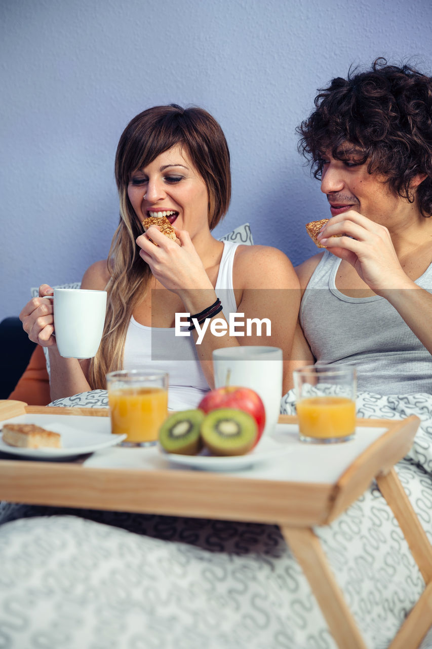 Couple having breakfast on bed at home