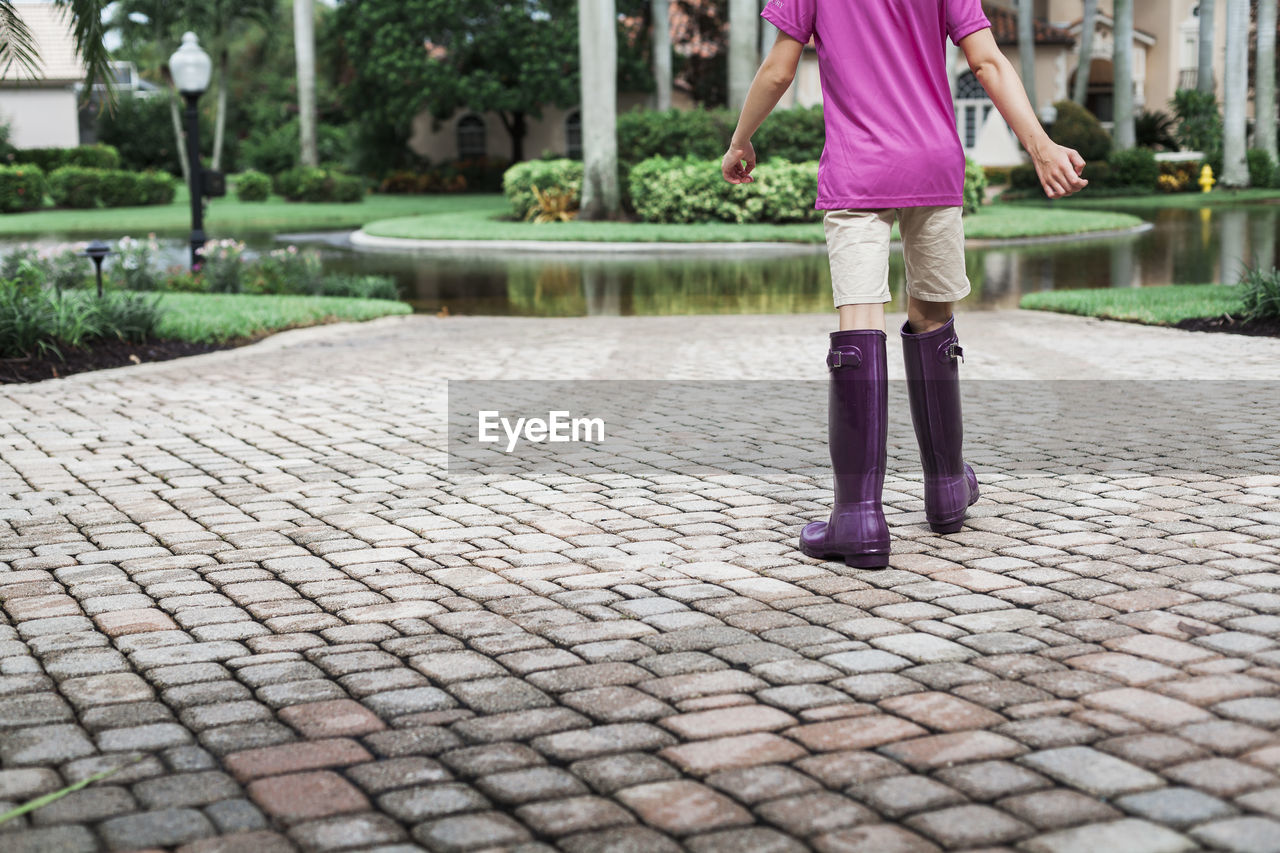 Young girl wearing purple boots walking in driveway