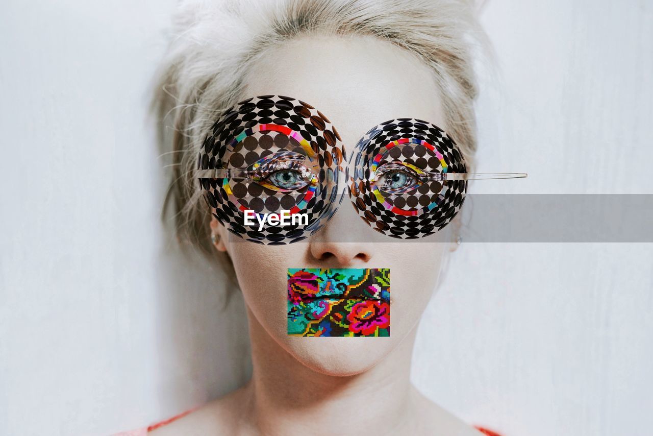 Digital composite image of woman with colorful pattern on face against wall
