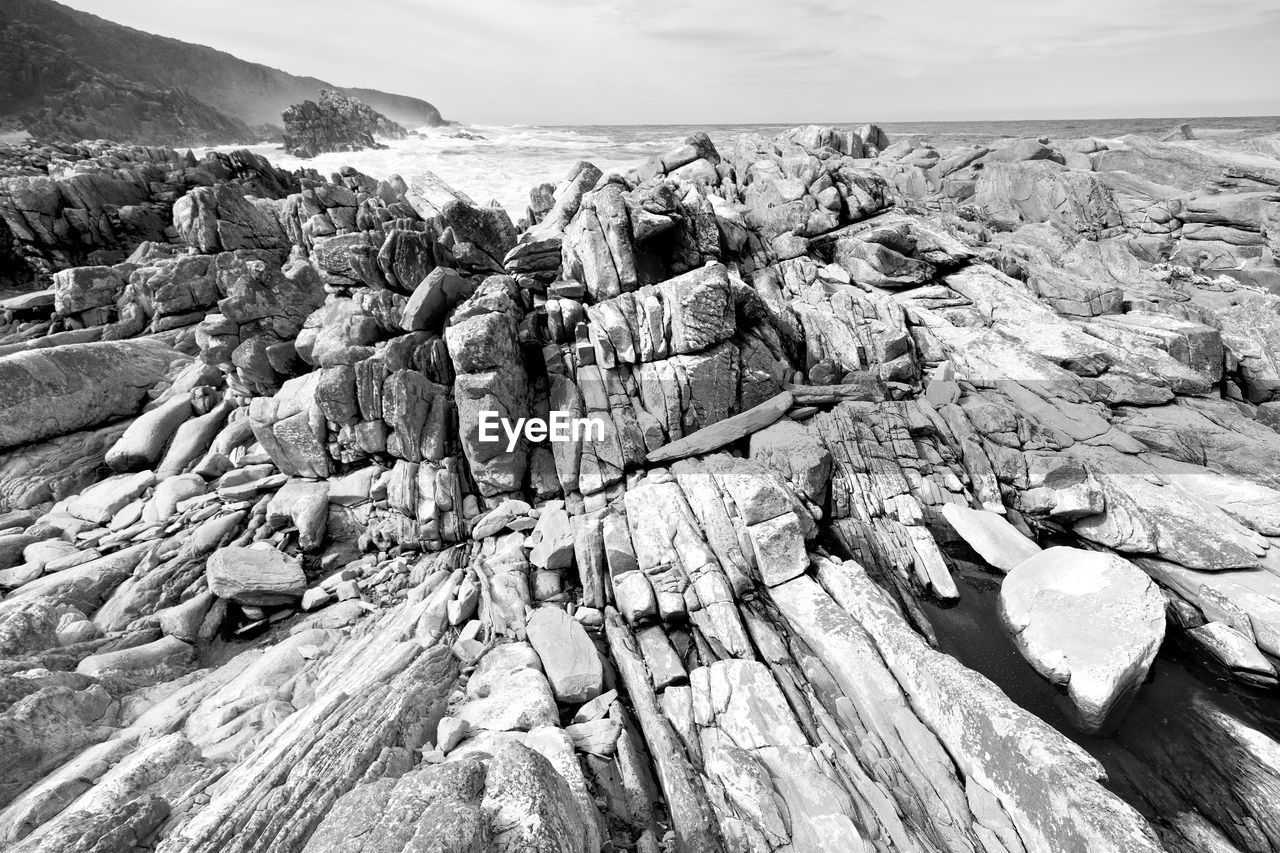 PANORAMIC SHOT OF ROCKS ON BEACH AGAINST SKY