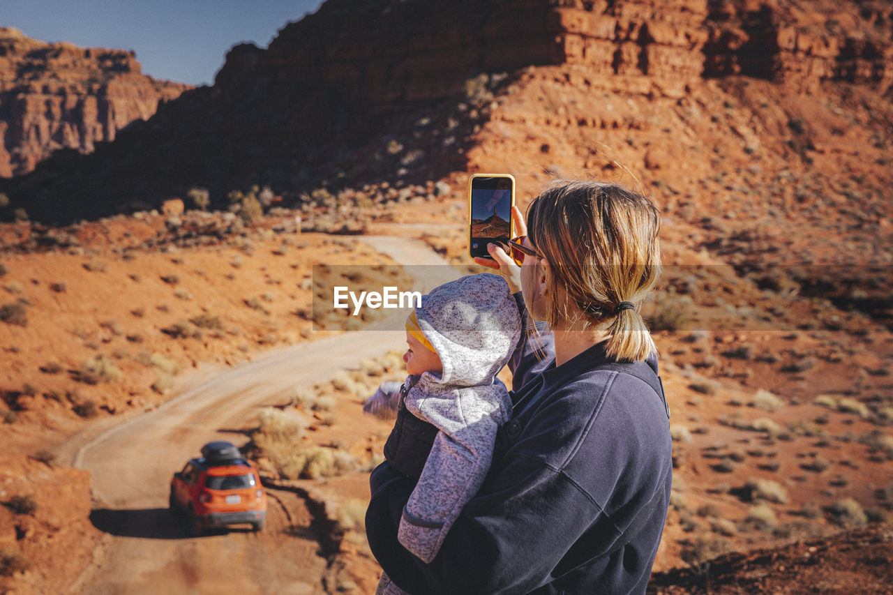 A woman with a child is taking pictures in valley of the gods, utah