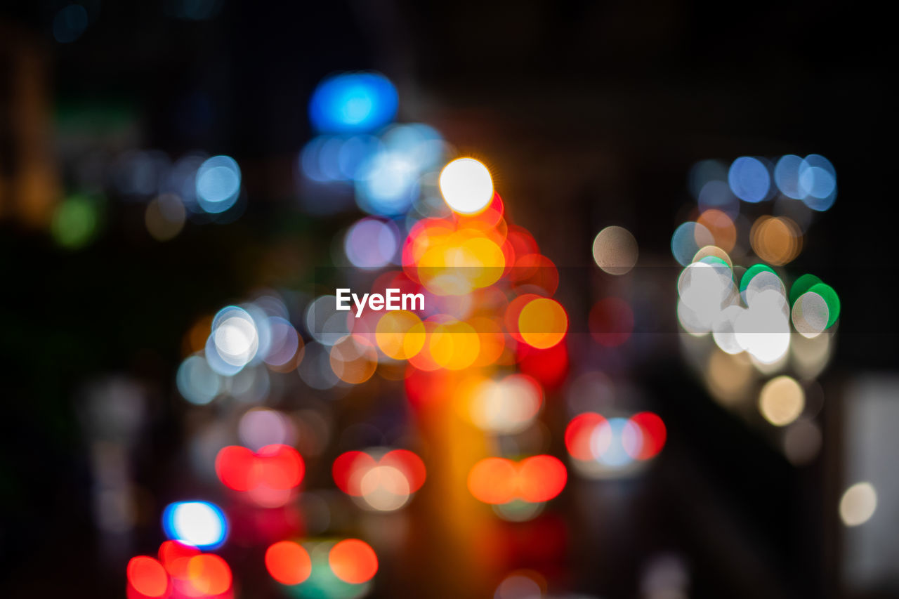 DEFOCUSED IMAGE OF ILLUMINATED LIGHTS ON STREET