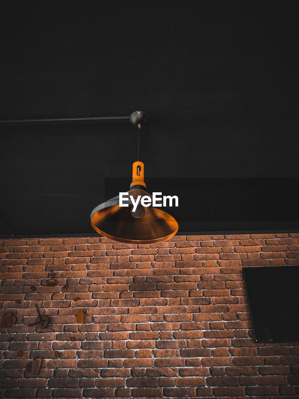 Low angle view of lighting equipment against brick wall