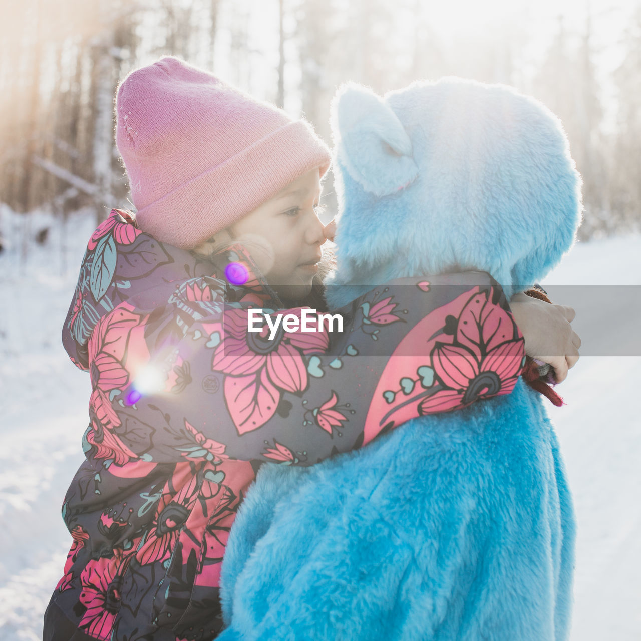 Father wearing costume with daughter on snowy field