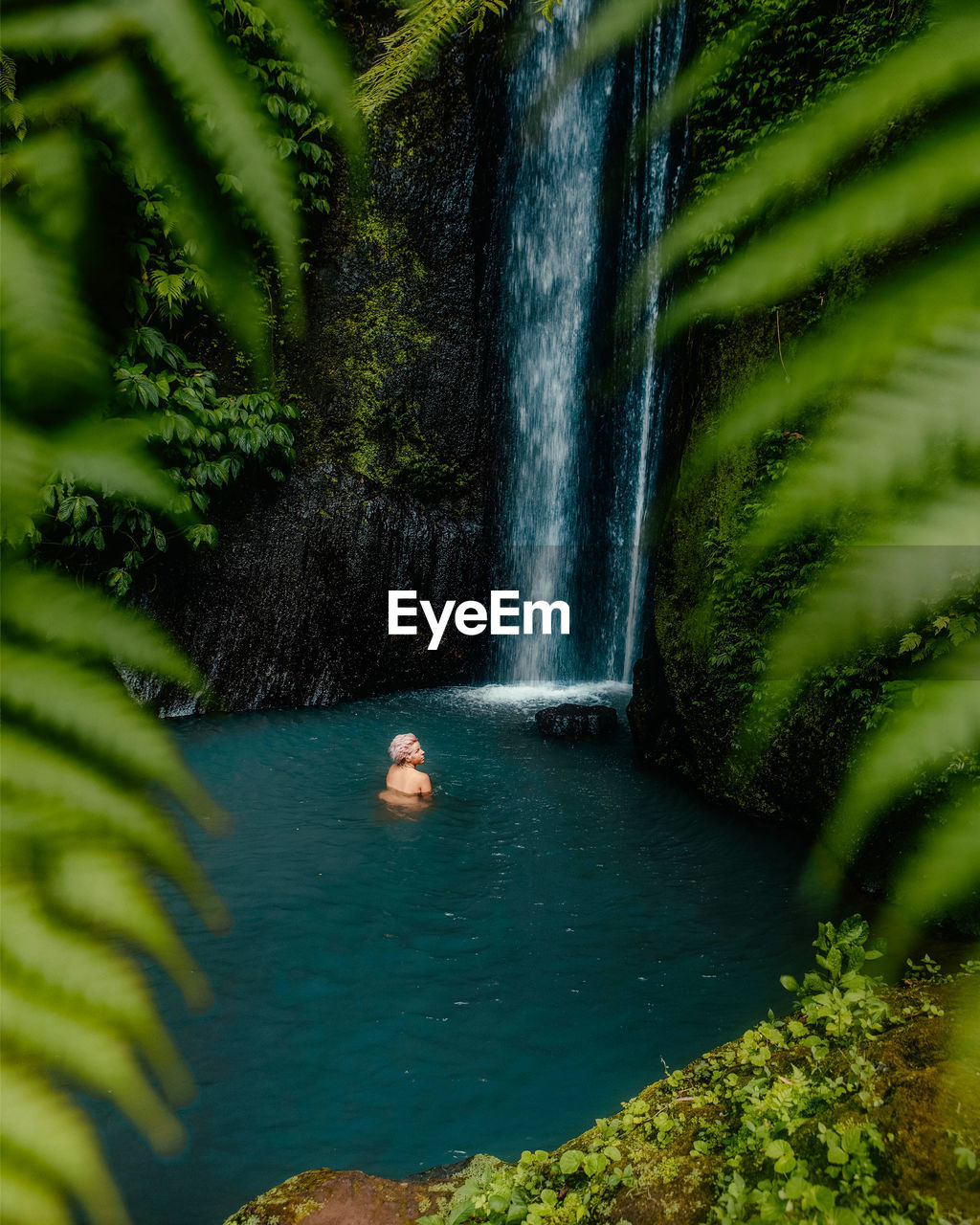 High angle view of woman enjoying waterfall in forest