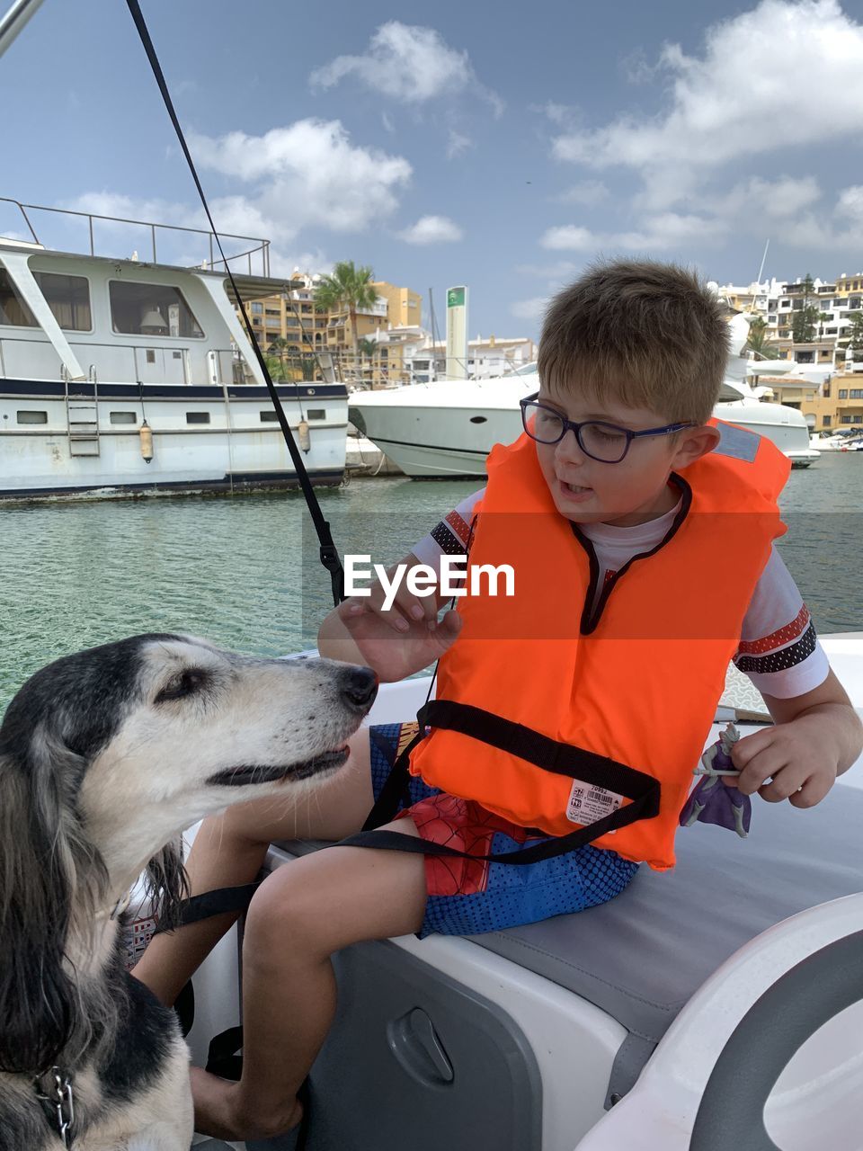 Young boy with saluki dog aboard boat in marbella, spain. 