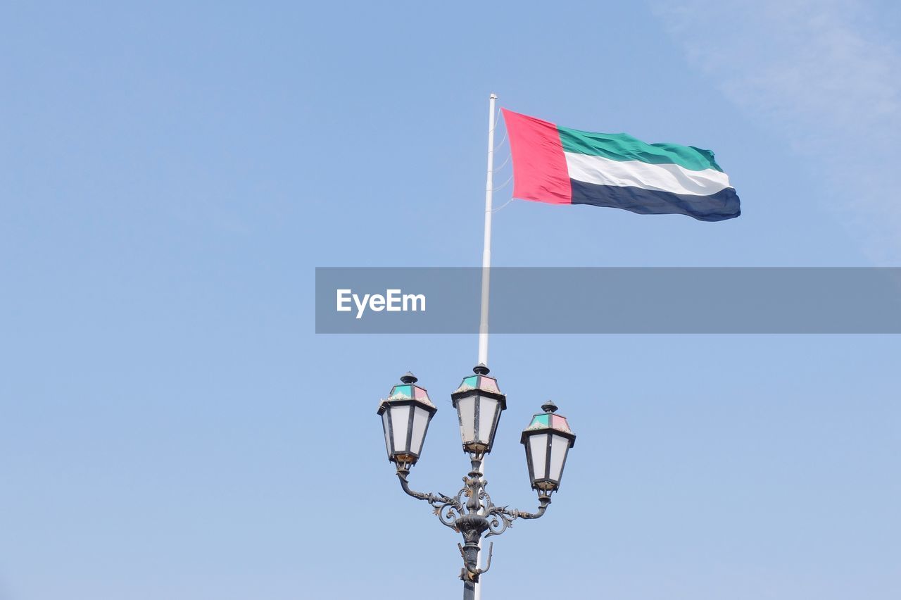 Low angle view of uae flag against blue sky