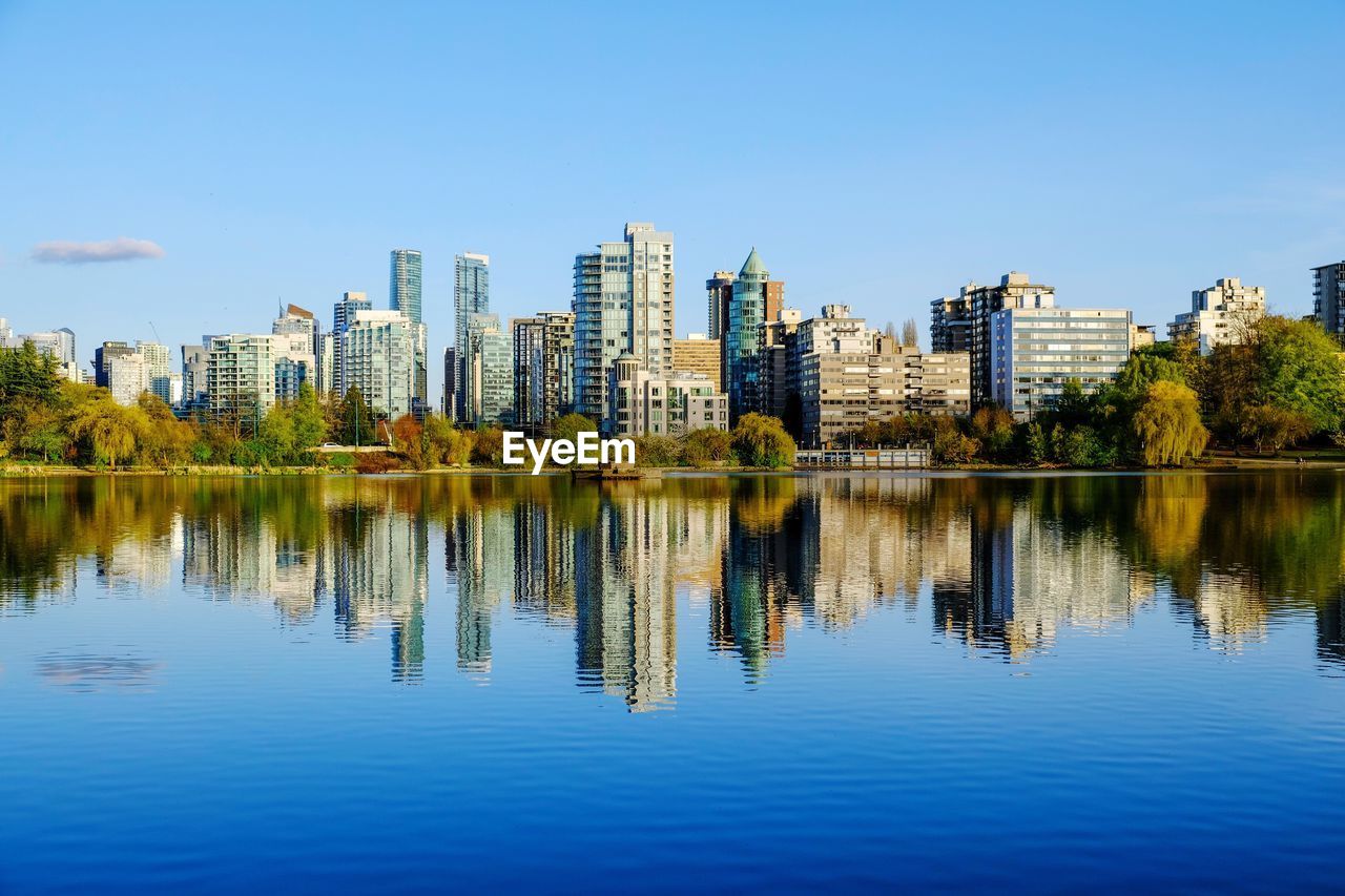 REFLECTION OF BUILDINGS IN LAKE AGAINST SKY