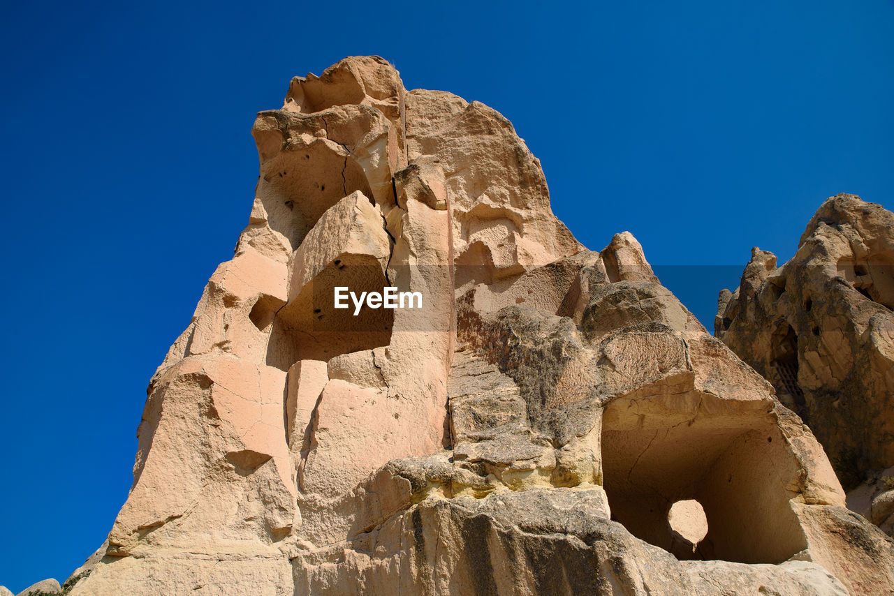 LOW ANGLE VIEW OF ROCK FORMATIONS AGAINST BLUE SKY