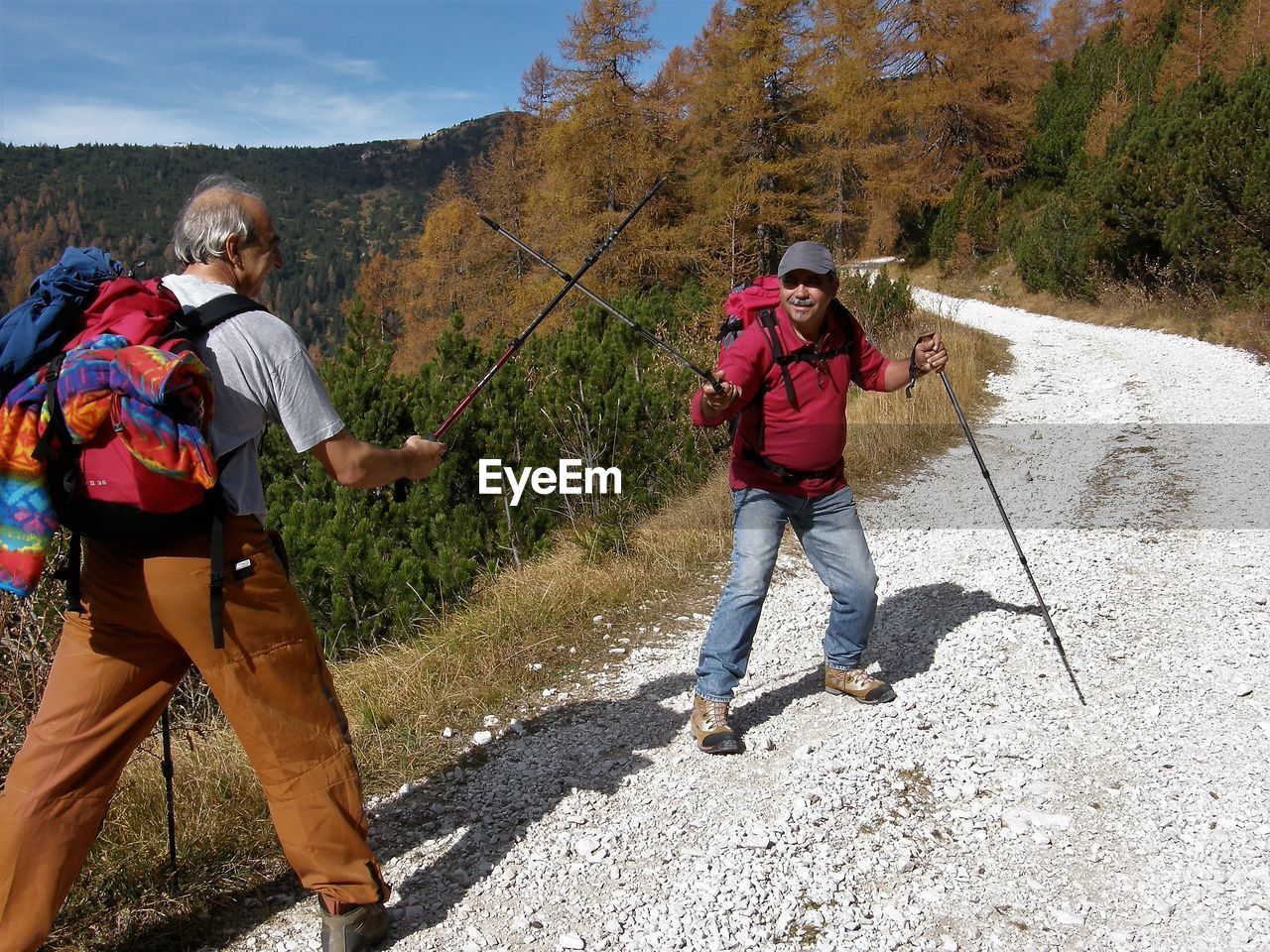 Cheerful of people playing with hiking pole on dirt road