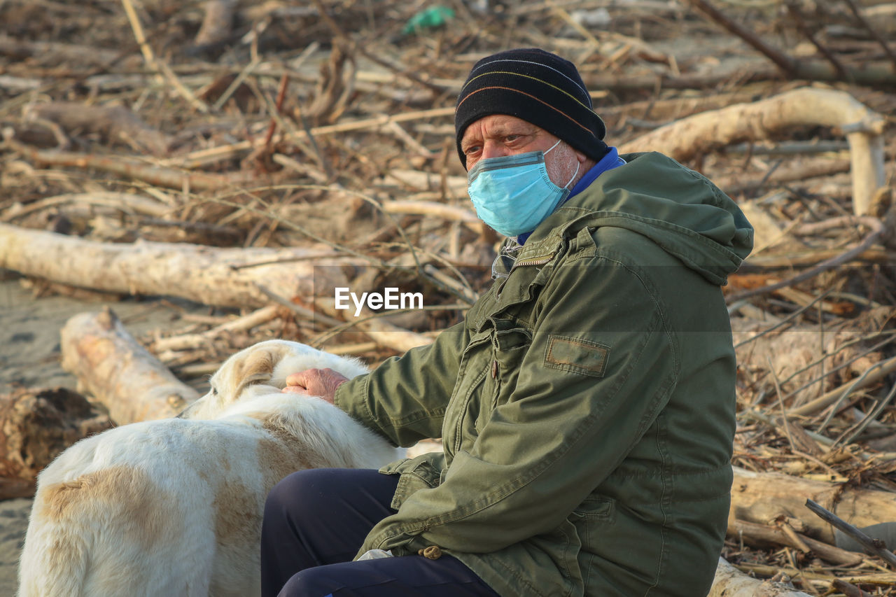Senior man wearing mask with dog outdoors