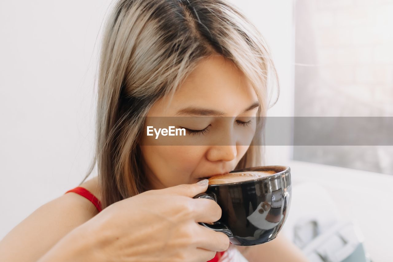 close-up of woman holding wineglass against white background