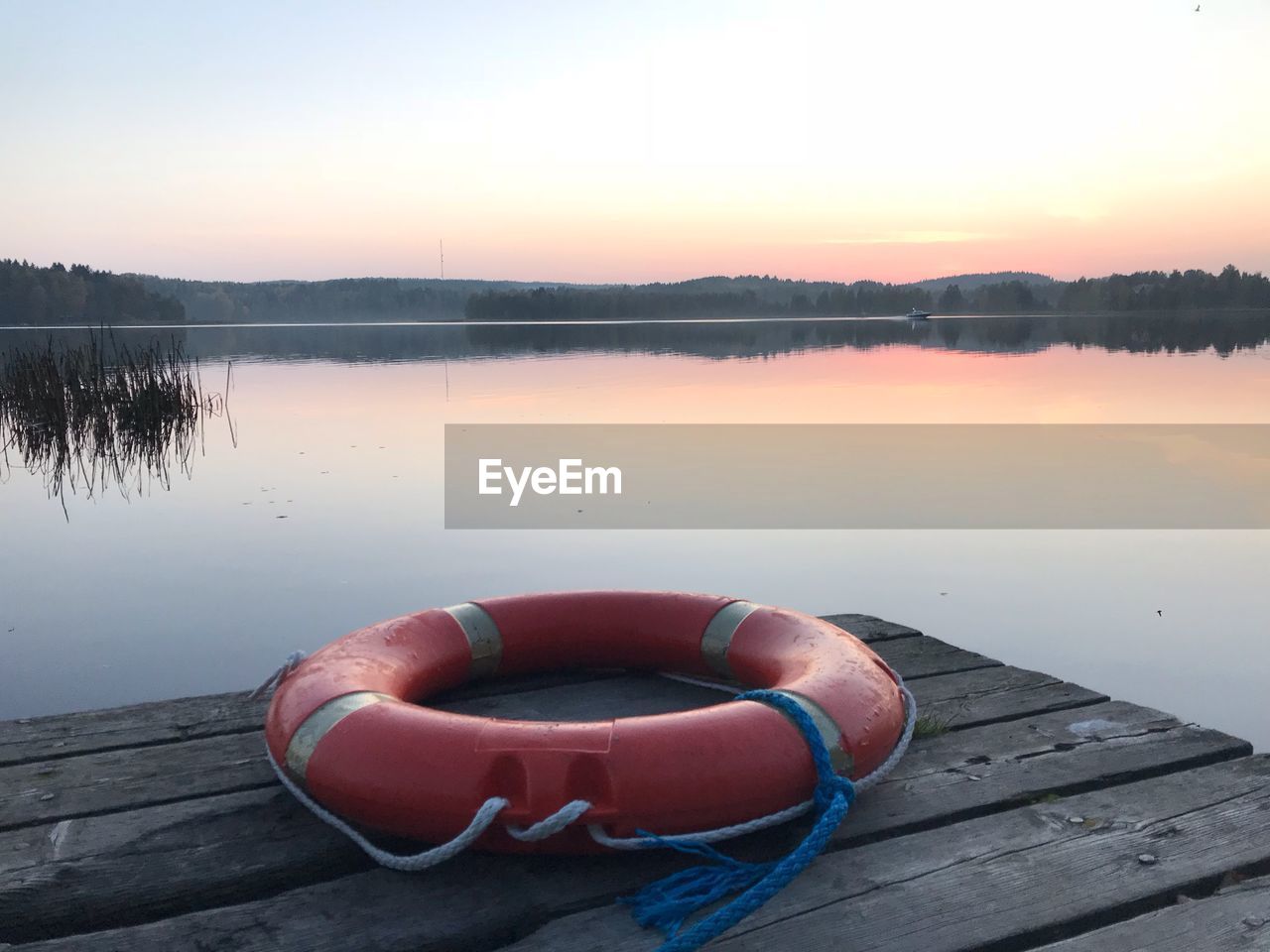 Pier on lake against sky during sunset