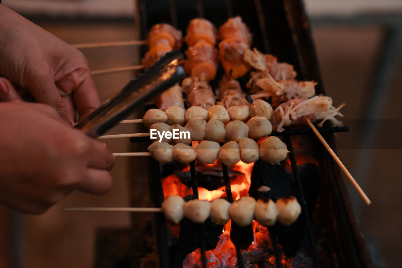 Midsection of person preparing food on barbecue grill