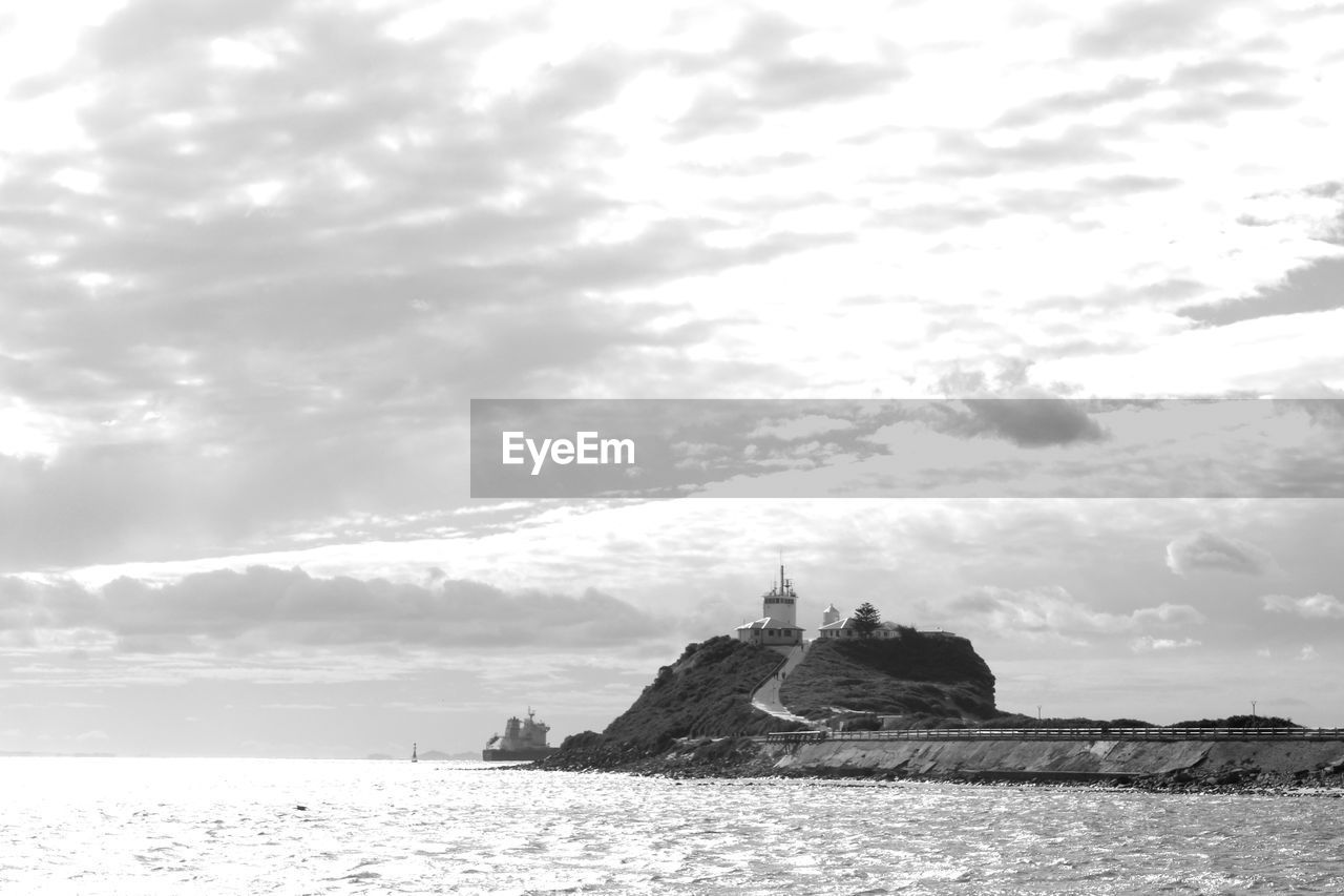 Lighthouse by sea against sky