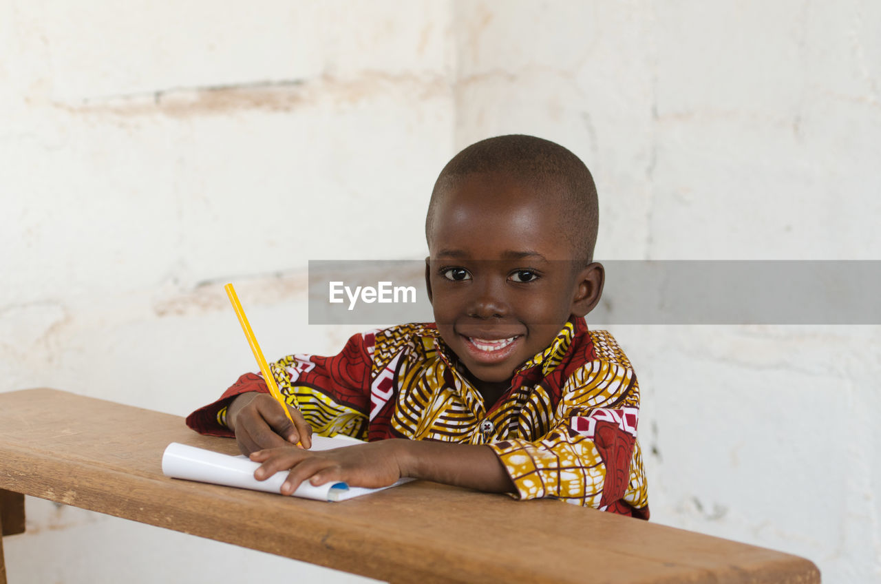 Portrait of smiling boy writing in book