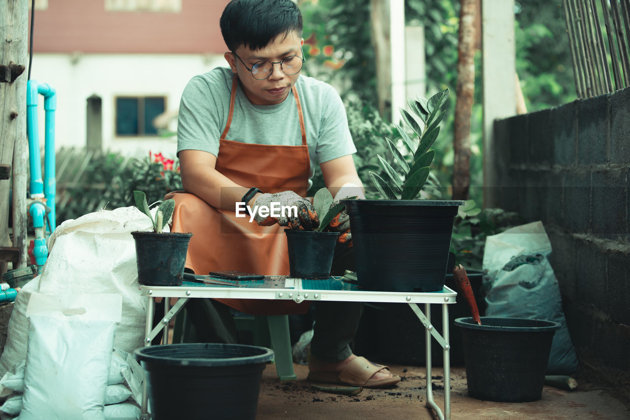 FULL LENGTH OF MAN SITTING IN BACKYARD