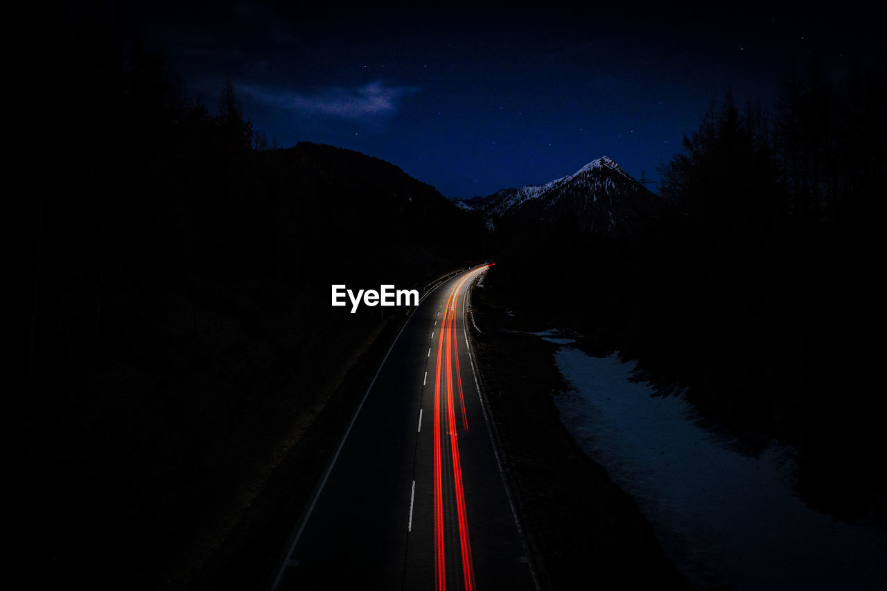 Light trails on road against sky at night