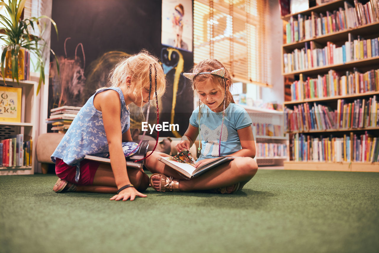 Two primary schoolgirls doing homework in school library. students learning from books