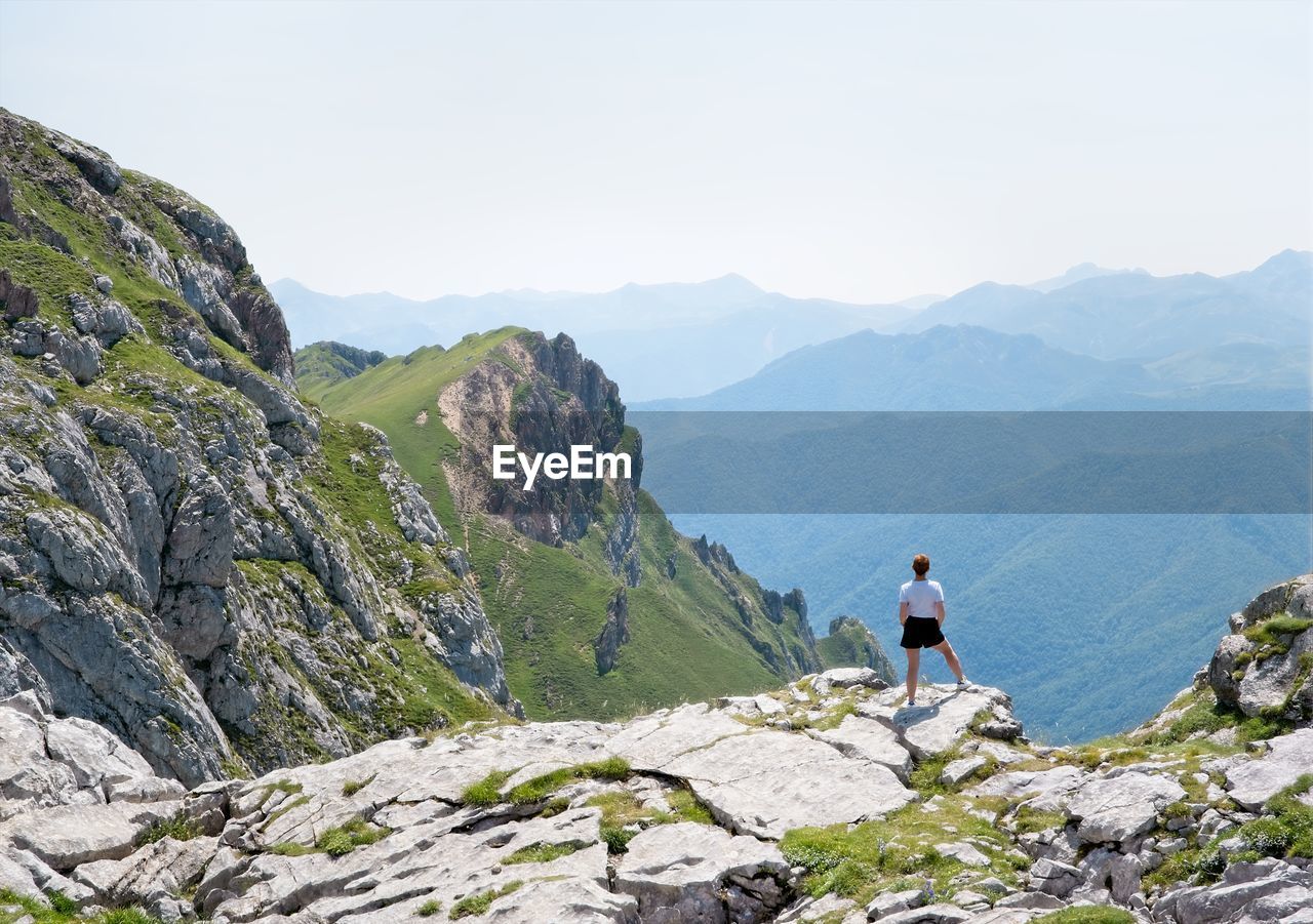 A woman looks at the landscape from the top of a mountain