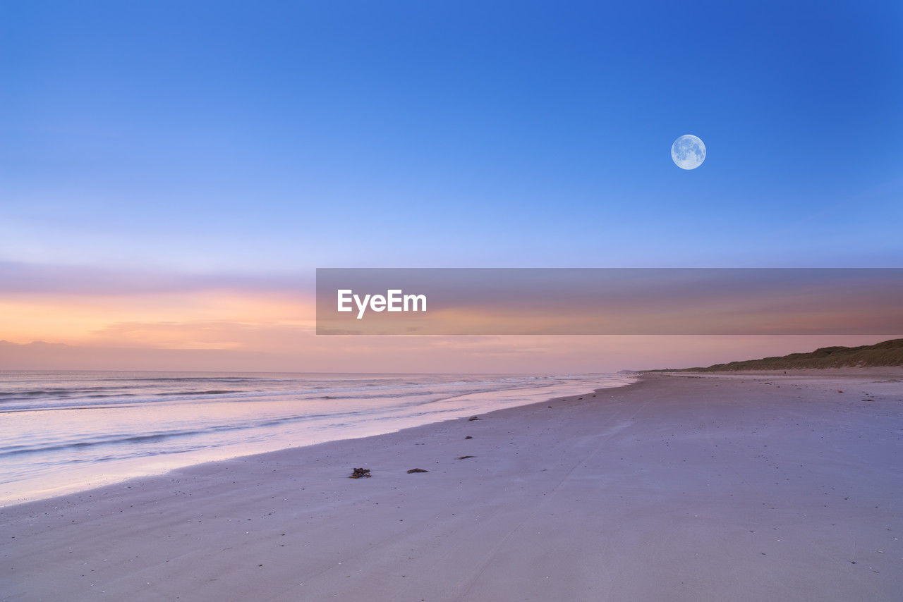 scenic view of beach against clear sky during sunset