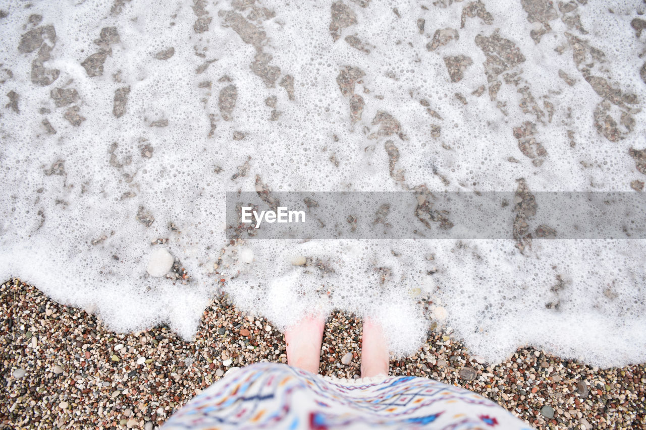 LOW SECTION OF PERSON STANDING ON SAND