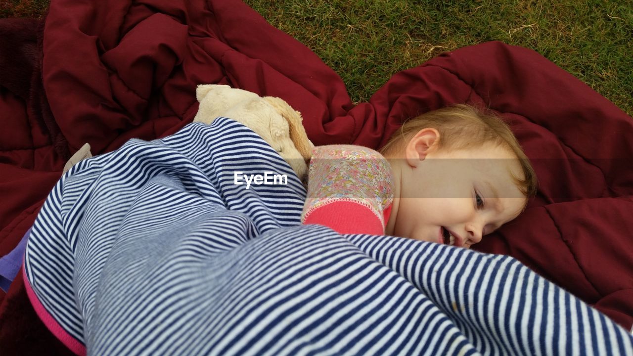 High angle view of toddler lying on blanket in yard